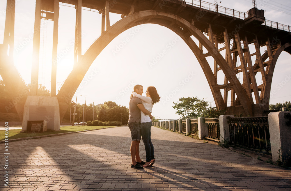Couple walking and having fun under the bridge at sunset Couple walking and having fun under the bridge at sunset