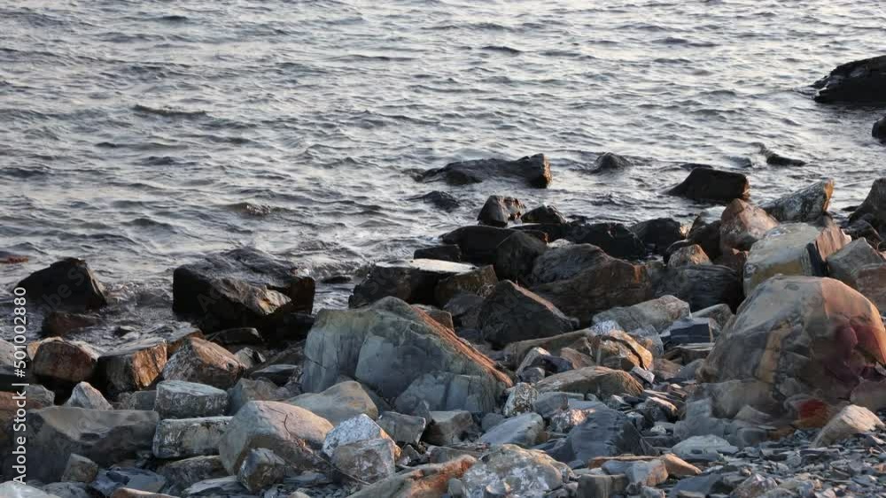 Sea Waves Breaking On Rocks And Beach Boulders In Summer Day At Sunset. Sea Waves Breaking On Rocks And Beach Boulders In Summer Day At Sunset.