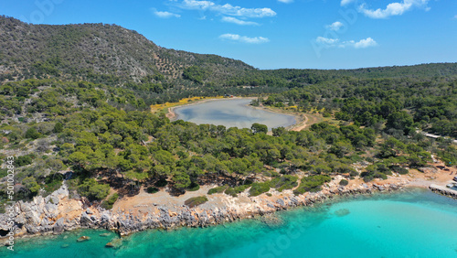 Aerial drone photo of iconic Aponisos bay and lake with clear turquoise sea and pine trees,  Agistri island, Saronic gulf, Greece © aerial-drone