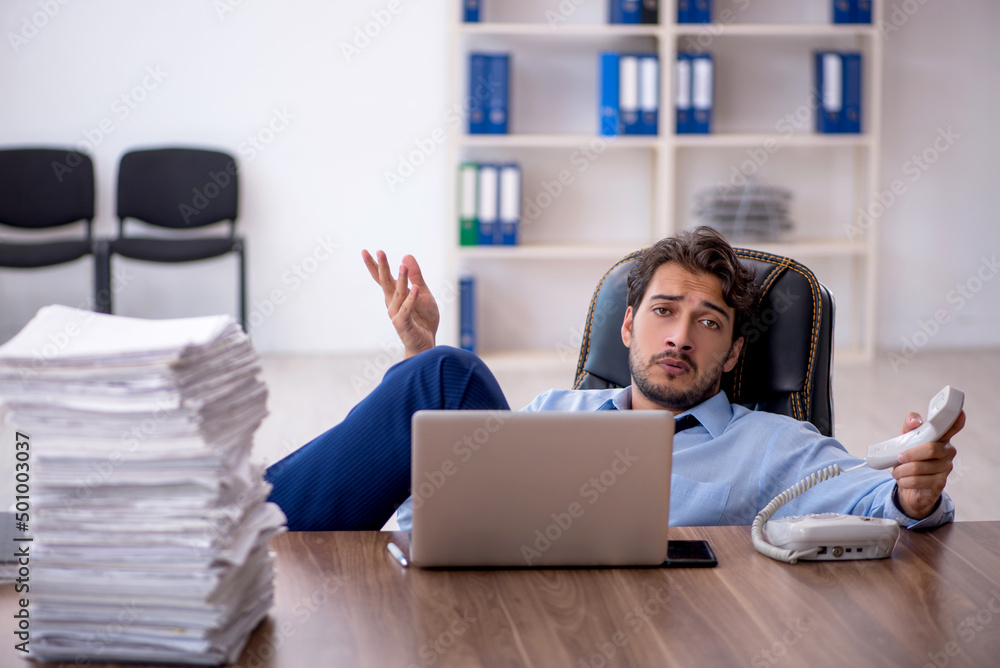 Young male employee and too much work in the office Young male employee and too much work in the office