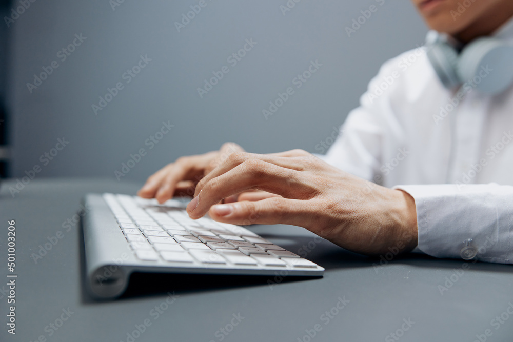 Asian man sitting at a table with a keyboard in the office technologies Asian man sitting at a table with a keyboard in the office technologies