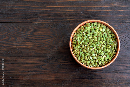Pumpkin seeds in a wooden spoon on a wooden background. Healthy food. Scattered seeds of pumpkin. Copy space