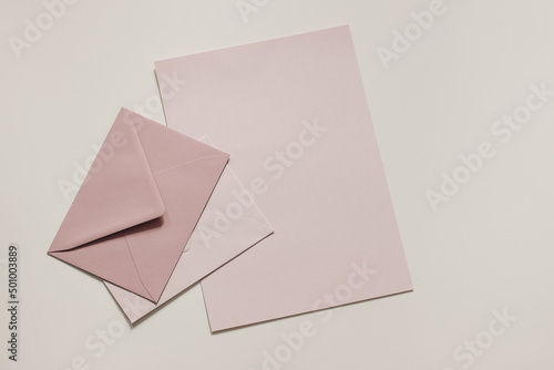 Set of pastel, blush pink blank envelopes and paper sheet mockups. Beige neutral background. Mailing, correspondence and post concept. Business, office stationery still life. Flat lay, top view.