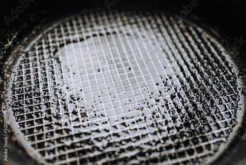 Background, texture, top view of a black round frying pan with a checkered pattern, after frying food, smeared with sunflower, olive oil. Photo of dishes.