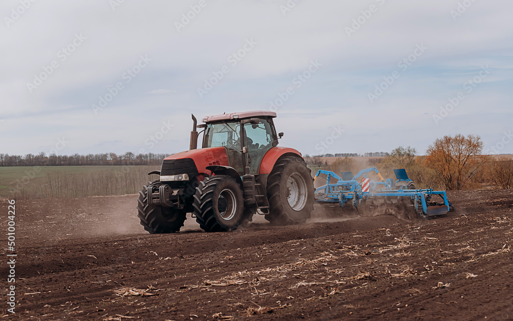 Spring sowing season. Farmer with a tractor sows corn seeds on his field. Planting corn with trailed planter. Farming seeding. The concept of agriculture and agricultural machinery. Spring sowing season. Farmer with a tractor sows corn seeds on his field. Planting corn with trailed planter. Farming seeding. The concept of agriculture and agricultural machinery.
