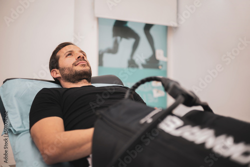 A man undergoes a pressotherapy treatment in an aesthetic clinic to relax his legs.