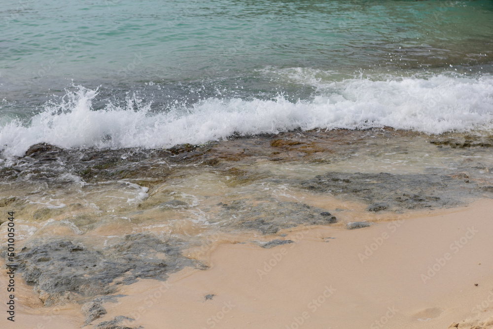A sea wave runs onto the shore and breaks on small rocks.A fragment of the seashore with rocks covered with algae.Beautiful color of water in the Caribbean Sea of the Dominican Republic A sea wave runs onto the shore and breaks on small rocks.A fragment of the seashore with rocks covered with algae.Beautiful color of water in the Caribbean Sea of the Dominican Republic