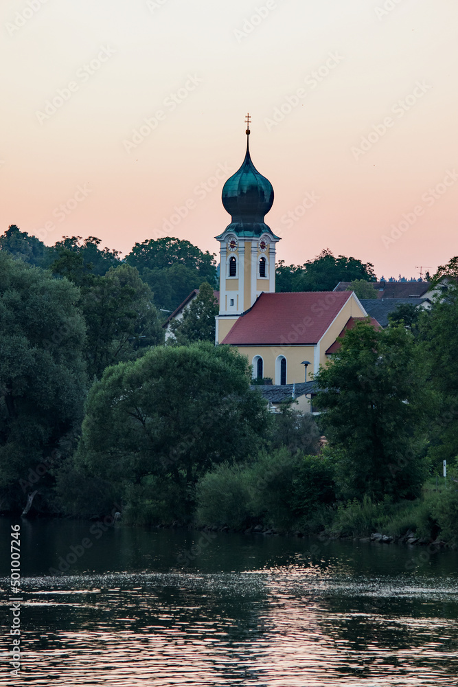 An onion domed church rises next to a river at dusk between Regensburg and Nuremberg, Germany.