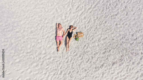 Aerial view of a young couple lying on the white sand. man and woman spend time together and travel through the desert.