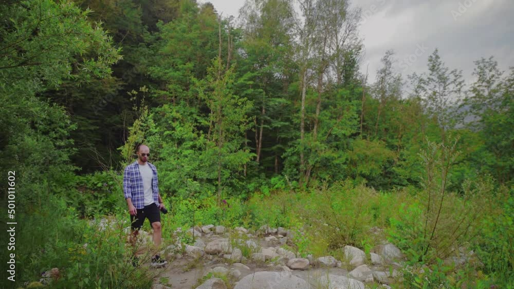A young man is walking in the forest and drinking water from a bottle. A man in the open air. Tourism A young man is walking in the forest and drinking water from a bottle. A man in the open air. Tourism