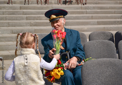 Foto PYATIGORSK, RUSSIA - MAY 09, 2011: Girl gives flowers to veteran on Victory Day