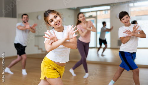 Portrait of tween girl doing exercises during family class in dance center