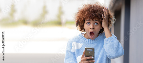 Obraz na plátně girl with mobile phone in the street and expression of surprise