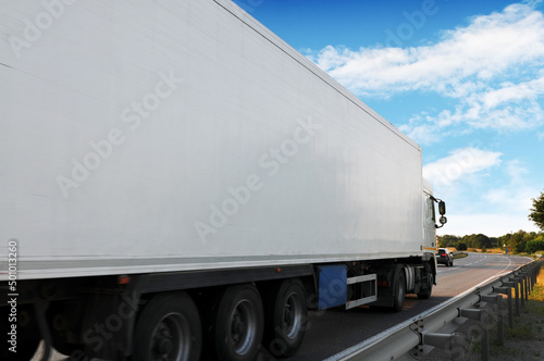 Close-up of the big truck with a trailer on a countryside road against a sky with clouds