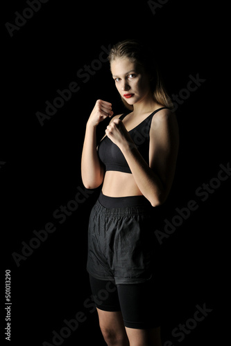 Young girl posing in fighting stance against a black background