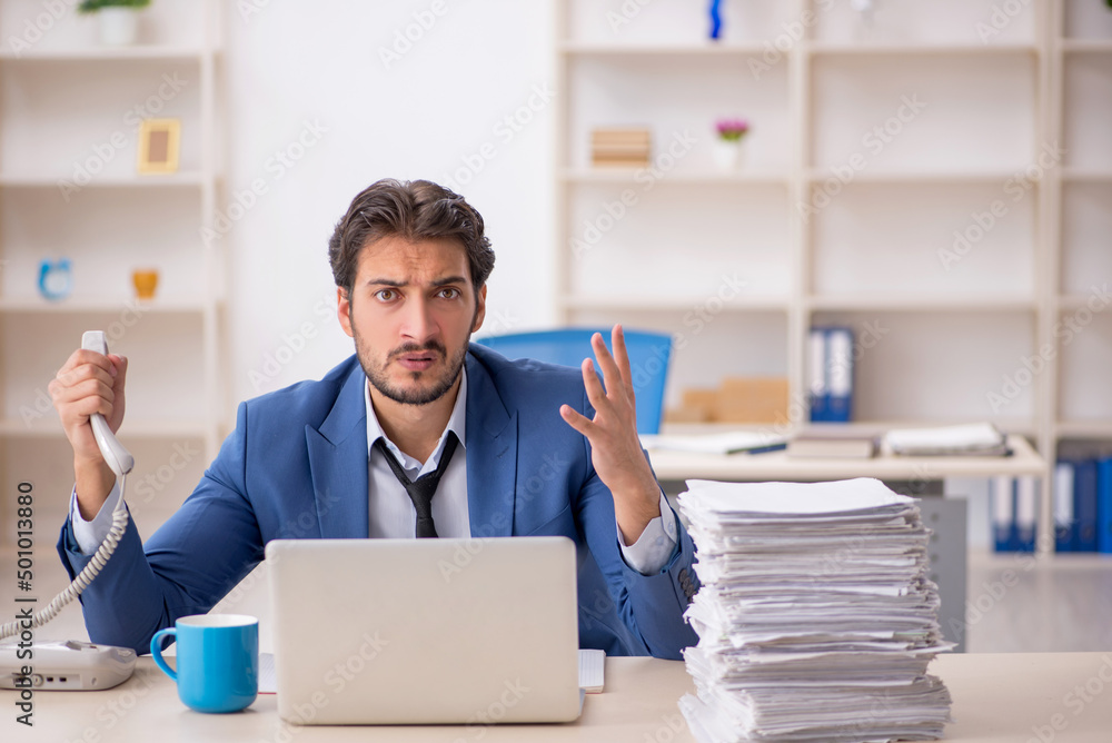 Young male employee and too much work in the office Young male employee and too much work in the office