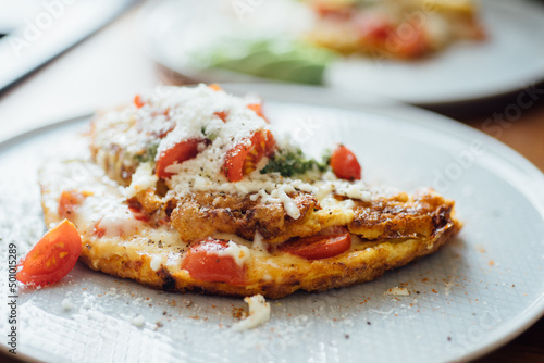 Plate with homemade breakfast: omelet with cheese and tomatoes.