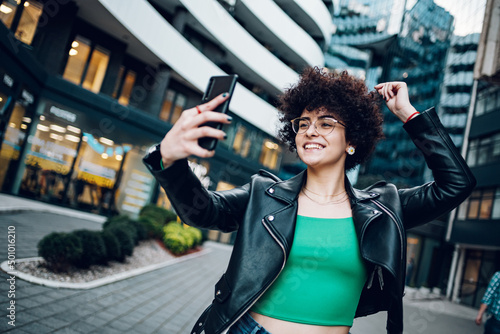 Woman with afro taking a selfie with a smartphone outside in the city photo