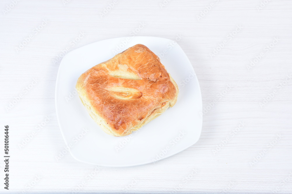 Ham and cheese puff pastry, accompanied by corn sauce on a wooden background