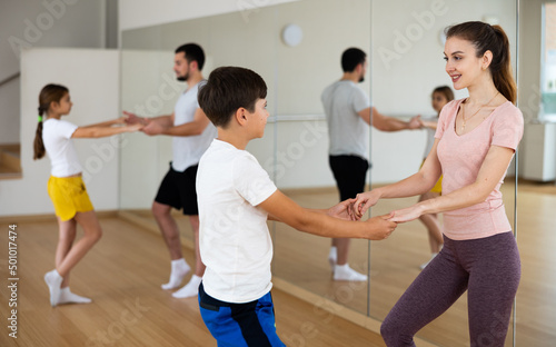 Mother and young son learning to dance waltz during group family classes.