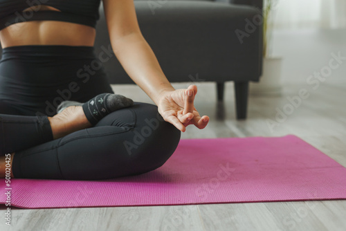 Attractive wellness Asian young woman sit on carpet breathing with yoga lotus pose, Yoga Exercise for Wellness Concept, Close up shot.