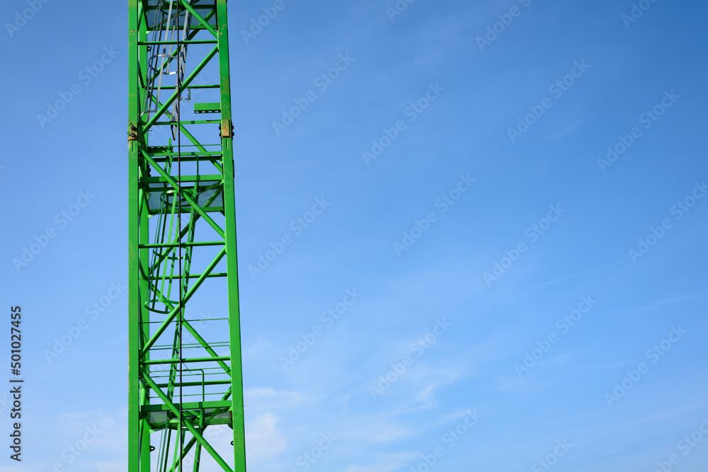 Green crane poles and ladder in the sky