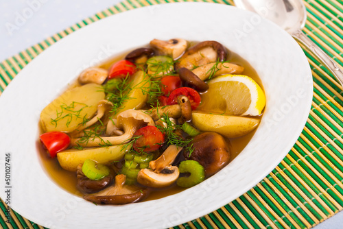 Delicious soup in rustic style with assorted mushroom, potatoes, tomatoes, celery and herbs