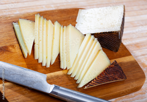 Slices of semi-hard spanish sheep cheese on wooden background