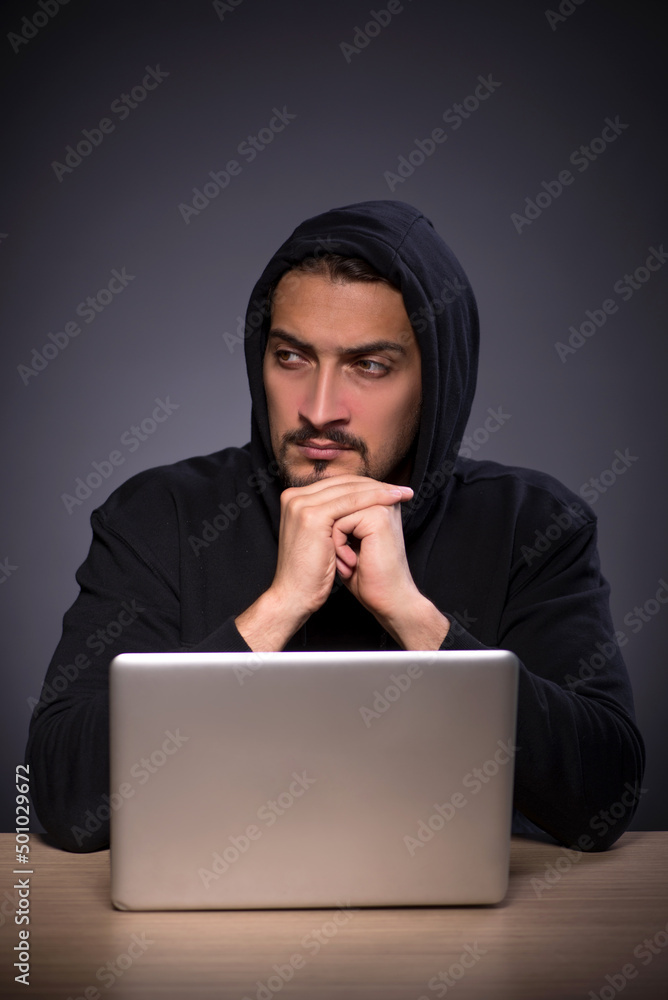 Young male hacker on grey background Young male hacker on grey background