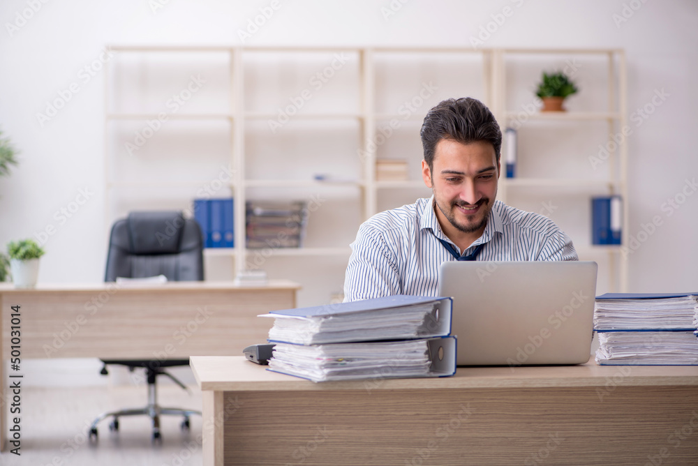 Young male employee and too much work in the office Young male employee and too much work in the office