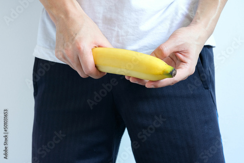 A young man holding a banana symbolizes the penis of a man in an erect state. photo