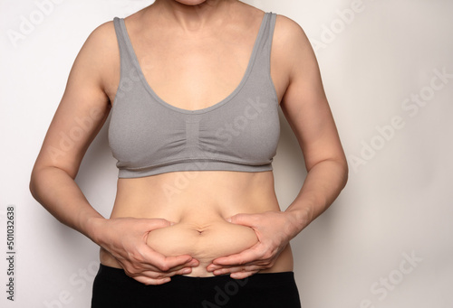 The girl shows that there is a little fat on her belly.Overweight fatty belly of woman. Fat unhealthy woman body.