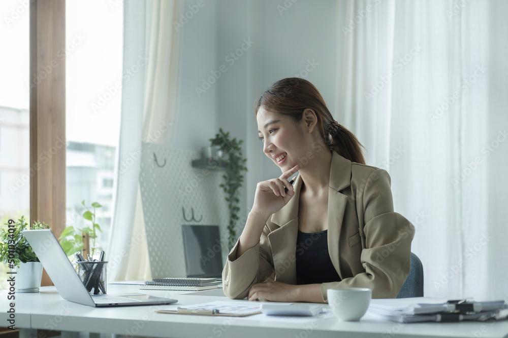 Gorgeous young businesswoman sitting in bright office and looking at computer laptop screen. Gorgeous young businesswoman sitting in bright office and looking at computer laptop screen.