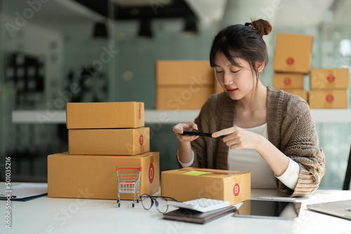 Young asian businesswoman owner packing and take a photo on cardboard box, Young Owner Woman Start up for Business Online. People with online shopping SME entrepreneur or freelance working concept