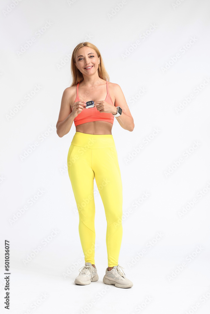 Female runner with pulse oximeter on light background Female runner with pulse oximeter on light background