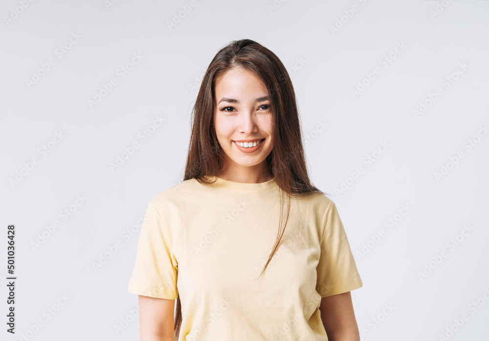Young happy asian woman winner with long hair in yellow shirt on grey background Young happy asian woman winner with long hair in yellow shirt on grey background