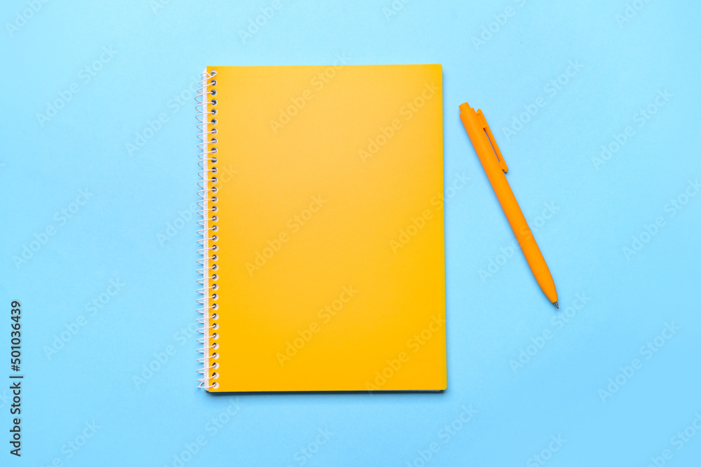 Yellow notebook and pen on color background