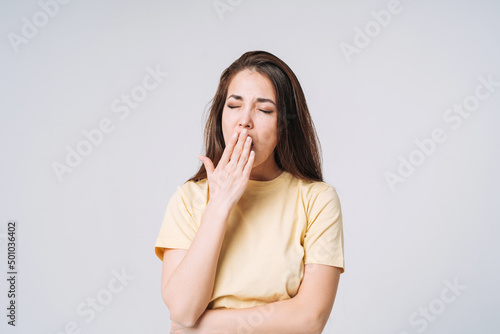 Young yawning asian woman winner with long hair in yellow shirt on grey background photo
