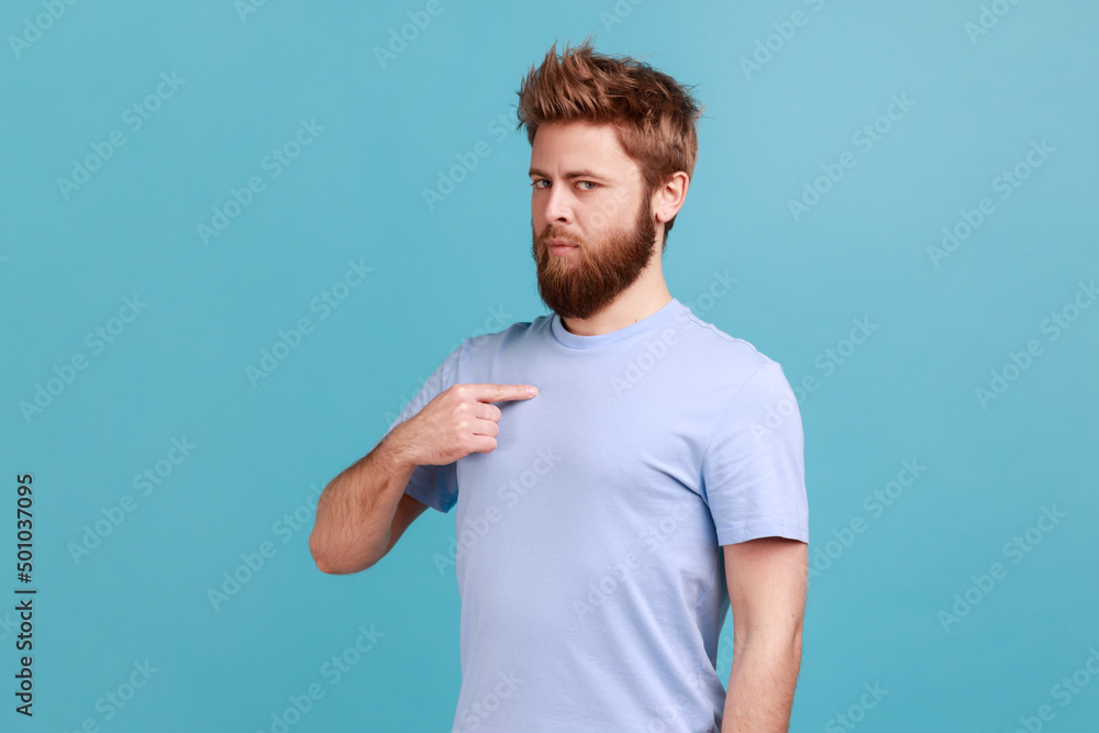 This is me. Portrait of self-confident narcissistic bearded man standing pointing himself, feeling self-important, proud, famous. Indoor studio shot isolated on blue background. This is me. Portrait of self-confident narcissistic bearded man standing pointing himself, feeling self-important, proud, famous. Indoor studio shot isolated on blue background.