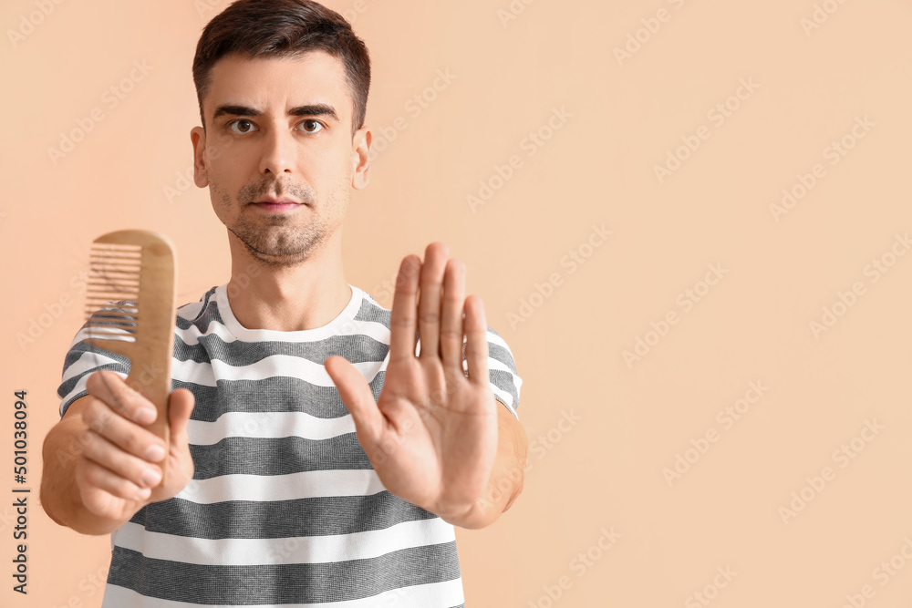 Handsome man with comb showing stop gesture on beige background Handsome man with comb showing stop gesture on beige background