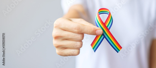 hand holding LGBTQ Rainbow ribbon for Support Lesbian, Gay, Bisexual, Transgender and Queer community and Pride month concept