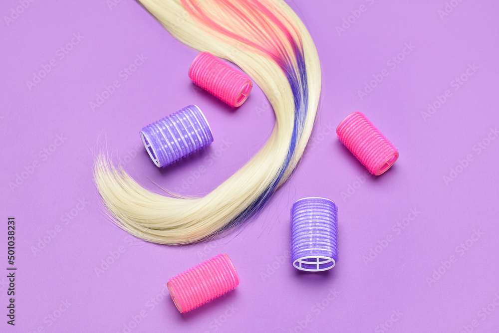 Long hair strand and curlers on color background Long hair strand and curlers on color background