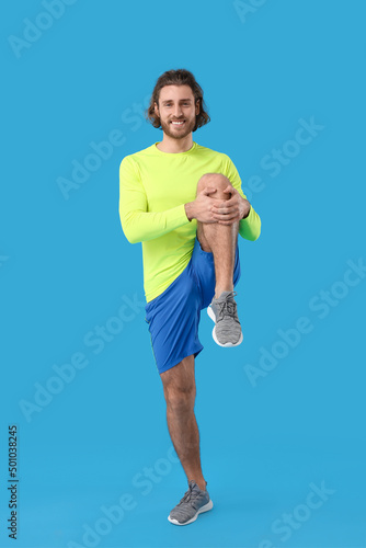 Sporty man stretching on blue background