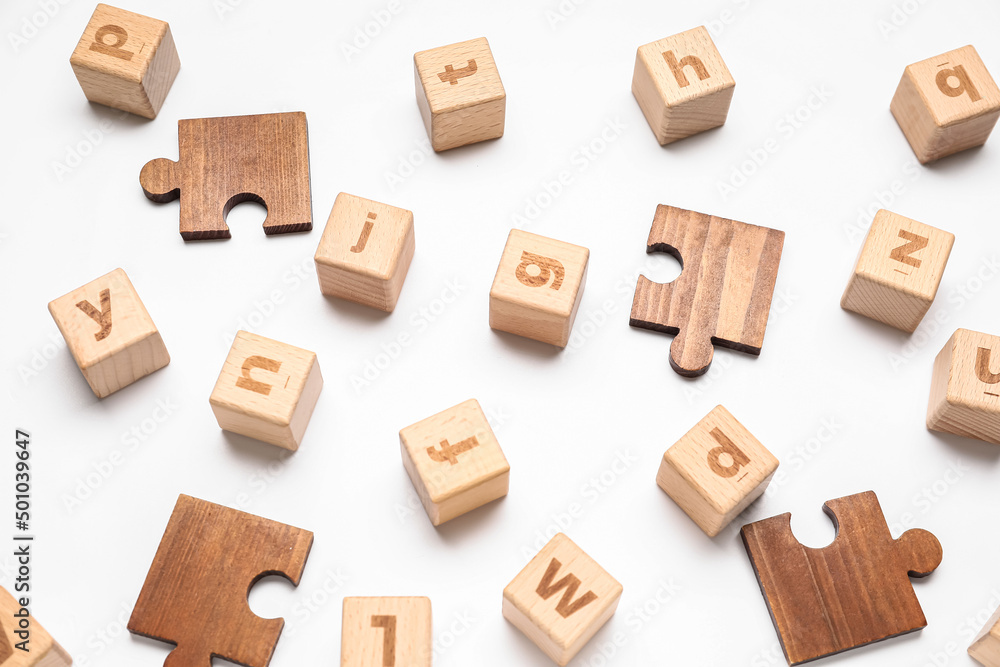 Fototapeta premium Wooden cubes with letters and puzzle pieces on white background