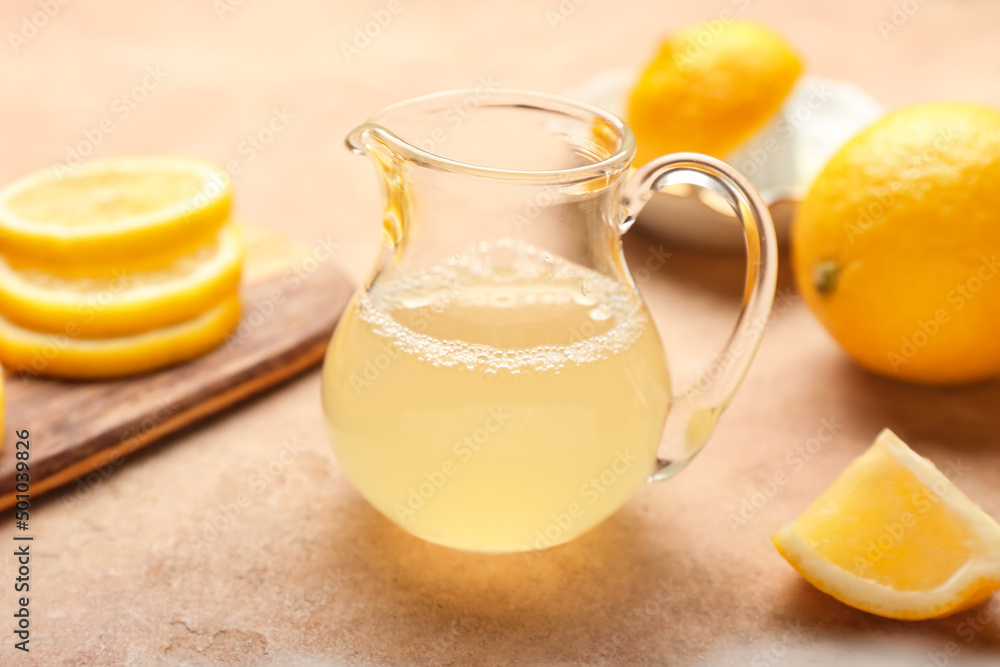 Jug of fresh lemon juice on color background Jug of fresh lemon juice on color background