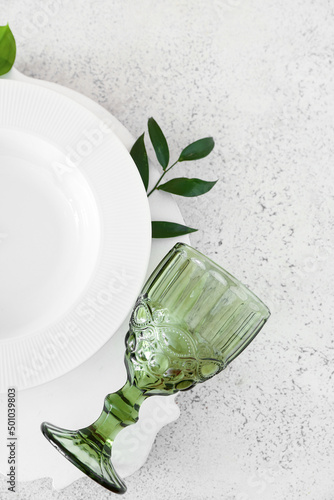 Stylish table setting and green leaves on light background