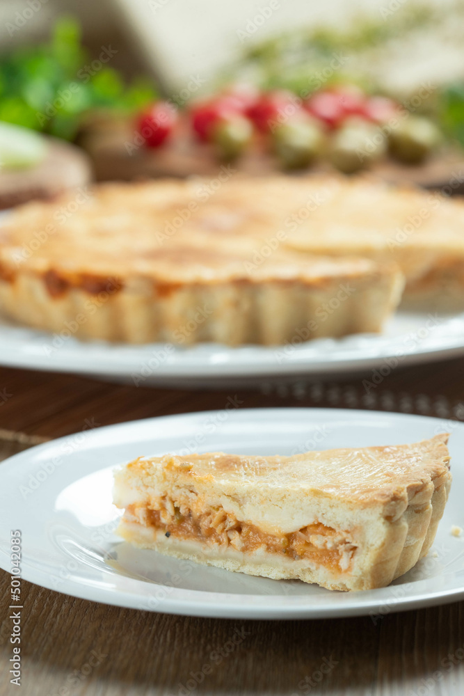Close up piece of Chicken pie with cottage cheese, tomatoes, onion and olives on wooden table and white plate.