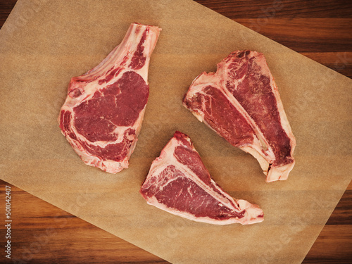 Three Raw Steaks on Parchment Paper.
