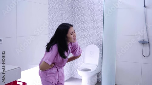 Young woman suffering stomach ache in bathroom