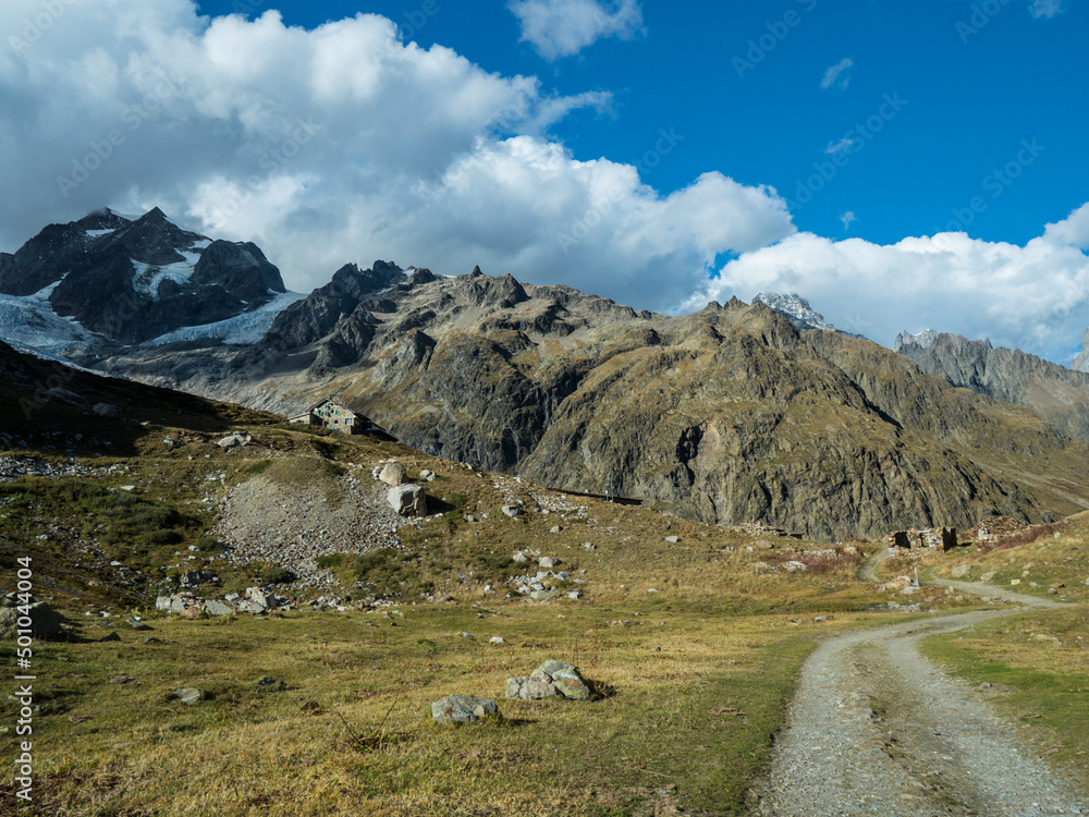 The road to the mountain shelter against the background of a cloudy sky. Tour du Mont Blanc
